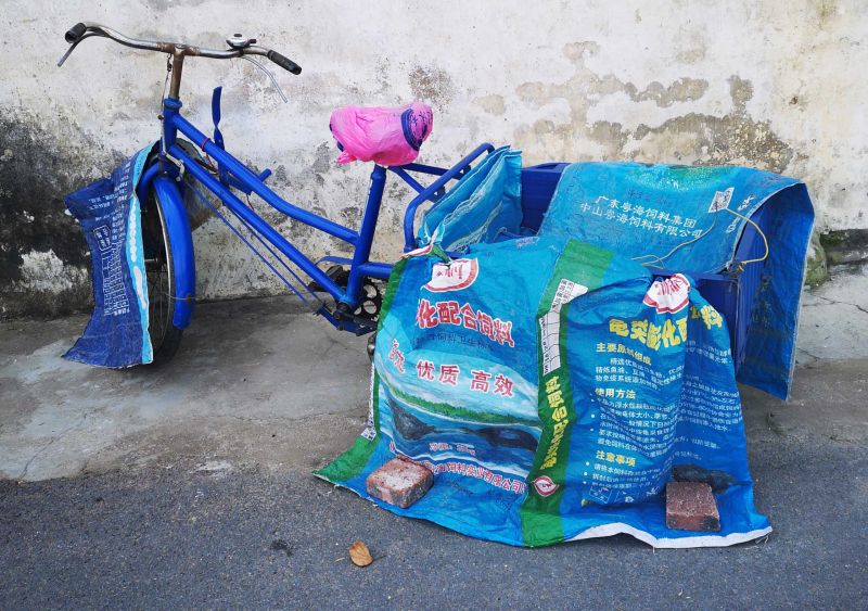 A tricycle covered by empty aquafeed bags, taken in Xingtan Town, Shunde District, Foshan
Photo by Xi Lei